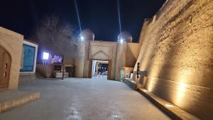 an empty alley with a stone wall at night at Ulli Oy Hotel & Terrace in Khiva