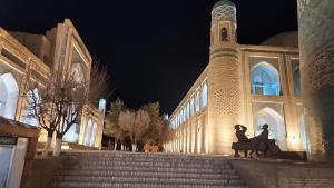 un edificio con una torre dell'orologio e una statua di due persone di Ulli Oy Hotel & Terrace a Khiva