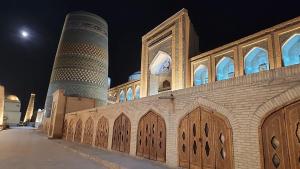 un edificio con un minarete y una mezquita por la noche en Ulli Oy Hotel & Terrace en Khiva