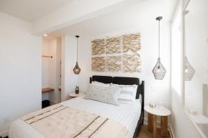a white bedroom with a large bed with white sheets at The Oceanic at The Tarrymore in Wrightsville Beach