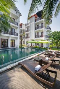 una piscina con tumbonas y un hotel en RAON Hoi An - STAY 24H, en Hoi An