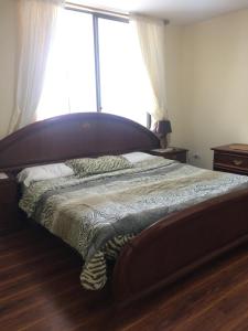 een bed in een slaapkamer met een groot raam bij Apartamento CENTRO de Loja. in Loja