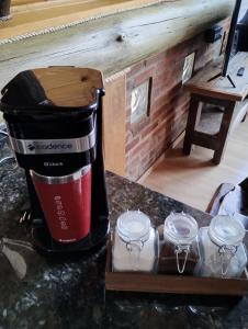 a coffee maker on a counter with four glass jars at Pousada Emerich in Cambara do Sul