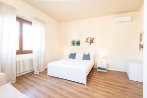 een witte slaapkamer met een wit bed en een raam bij Donatello Apartments by Firenze Prestige in Florence