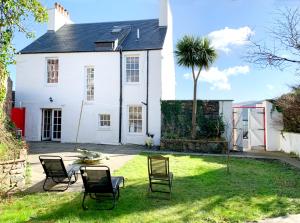 a white house with chairs and a palm tree at Sandbankhouse Campbeltown in Campbeltown