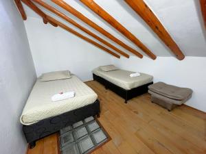 2 camas en una habitación con suelo de madera en CASA VACACIONAL SAN MARCOS, en Villa de Leyva