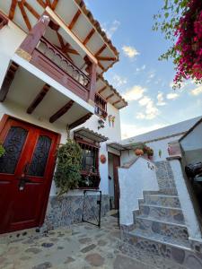 una casa con una puerta roja y escaleras delante en CASA VACACIONAL SAN MARCOS, en Villa de Leyva