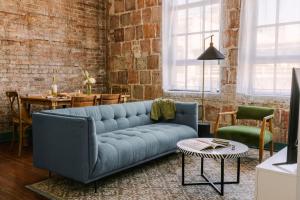 a living room with a blue couch and a brick wall at Sonder The Schaeffer in New Orleans