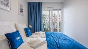 a bedroom with a bed with blue pillows and a window at Lazurowe Wybrzeże z widokiem na morze - Perłowa Przystań - Holiday City in Sianozety +49 photos