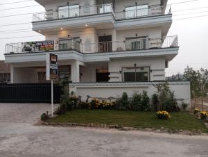 拉合爾的住宿－Hotel Luxe Heights Lahore，前面有标志的白色建筑