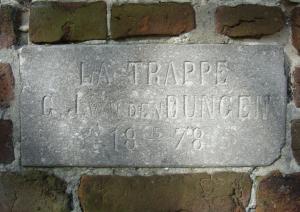 un panneau en pierre sur un mur de briques avec les mots la trappe e e commerce dans l'établissement B&B Boerderij La Trappe Deurne, à Deurne