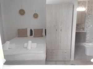 a white bedroom with a bed and a white cabinet at President Guest House in Keratokampos