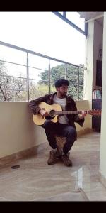 um homem sentado numa guitarra numa sala em mye Home stay near golden temple em Amritsar