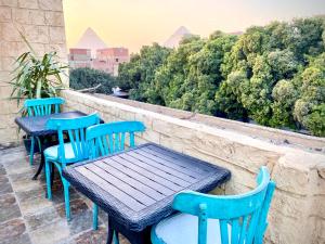 3 blaue Tische und Stühle auf einem Balkon mit Bäumen in der Unterkunft 4 Pyramids inn in Kairo