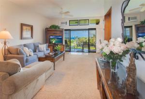 uma sala de estar com um sofá e uma mesa com flores em 412 Ridge em Kahana