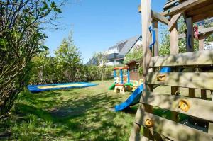 um quintal com um parque infantil com um escorrega em Haus am Meer F3 em Wenningstedt