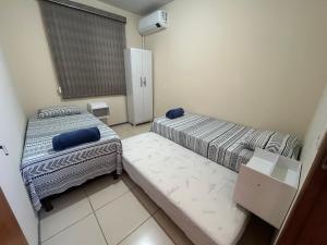 a small room with two beds and a window at Apt. Aconchegante in Araguari