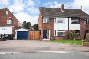 a red brick house with a blue garage at Stunning 3 Bed Home in Gloucester in Down Hatherley