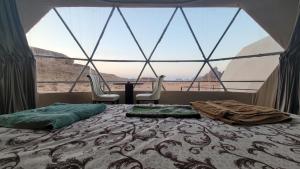 a bedroom with a bed and a large window at wadi rum guest house camp in Aqaba