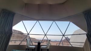 uma grande janela num quarto com uma mesa e cadeiras em wadi rum guest house camp em Aqaba