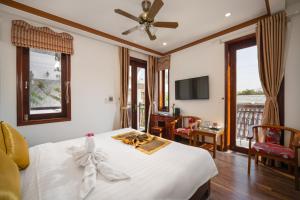 um quarto com uma cama branca e uma ventoinha de tecto em RAON Hoi An - STAY 24H em Hoi An