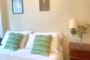 Una cama con almohadas verdes y blancas. en Casa PilarCasco Viejo Wifi, en Bilbao
