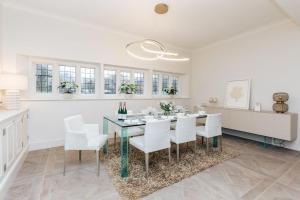 a white dining room with a table and white chairs at Wisteria House - Sleeps 11 in Buckinghamshire