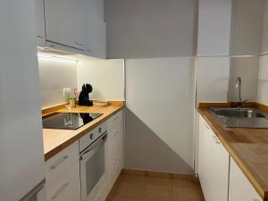 a small kitchen with white cabinets and a sink at Apartamento av.Galicia playa in Finisterre