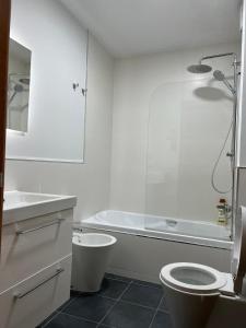 a bathroom with a toilet and a tub and a sink at Apartamento av.Galicia playa in Finisterre