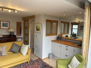 a living room with a yellow couch and a kitchen at Summer house studio in Cheltenham