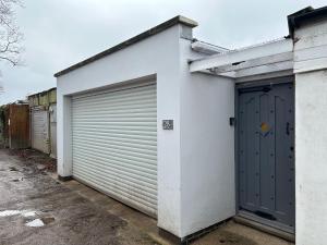 ein weißes Gebäude mit zwei Garagentüren darauf in der Unterkunft Summer house studio in Cheltenham