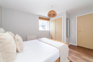 a bedroom with a white bed and a window at The Whitecross Street Apartment in London