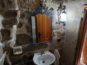 Baño de piedra con lavabo y espejo en Hotel O'Pazo en Vigo