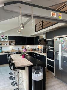 een keuken met zwarte kasten en een tafel. bij Superbe loft climatisé à Suresnes avec terrasse in Suresnes