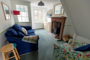 a living room with a blue couch and a fireplace at LITTLE BLUE HOUSE - Cottage with Seaview near the Lake District National Park in St Bees