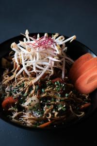 a black plate of food with noodles and vegetables at Prinsotel La Dorada & Spa in Playa de Muro