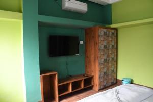 a bedroom with a green wall with a flat screen tv at Kajal's Home stay in Siliguri