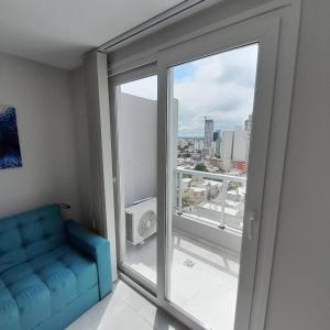 a living room with a blue couch and a window at Apart Clematis, 1 dormitorio céntrico con balcón. in Río Cuarto