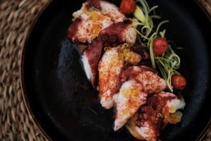 a black plate of food with meat and vegetables at Prinsotel La Dorada & Spa in Playa de Muro