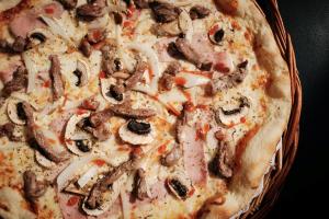 a pizza with meat and mushrooms in a basket at Prinsotel La Dorada & Spa in Playa de Muro