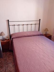 um quarto com uma cama com um edredão rosa em Alojamiento Auri em Almuñécar