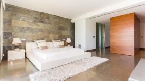 a bedroom with a white bed and a stone wall at SA PLATJA Etv in Playa de Muro