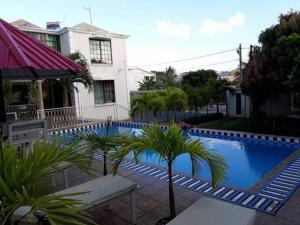 a swimming pool with palm trees in front of a house at Adorable 2bedroom homestay in Beau Bassin
