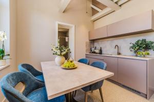 a kitchen with a wooden table and blue chairs at Villa Ghisi Apartments in Zadar