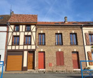 an old brick building with red and orange doors at Le Cœur du Bien-être - Gîte grande capacité - Superbe emplacement - Vue Seine - Décoration soignée - Coin touristique in Les Andelys