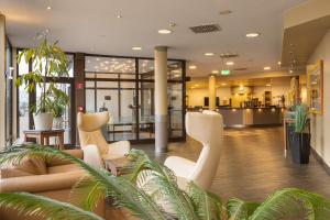 a lobby with white chairs and plants in a building at IFA Fehmarn Hotel & Ferien-Centrum in Burg auf Fehmarn