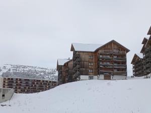 a building on top of a snow covered hill at Appartement cosy dans chalet vue Montagne in Le Dévoluy