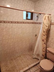 a bathroom with a toilet and a shower curtain at Casa ROMA in Ciudad Obregón
