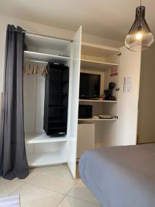 a bedroom with a white closet with a tv and a bed at Chambre confortable avec une entrée indépendante - Parking & accès Lille facile in Marcq-en-Baroeul