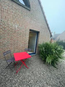 a red table and a chair next to a brick building at Chambre confortable avec une entrée indépendante - Parking & accès Lille facile in Marcq-en-Baroeul